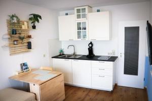 a kitchen with white cabinets and a sink and a table at Le Petit- Niedliches Ferienapartment mit Pool in Schluchsee