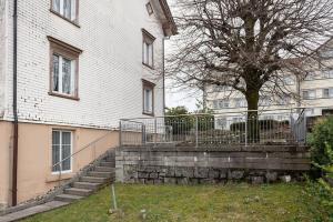 a white building with a staircase next to a tree at 11 - Gästehaus Erika - Hundwil - Appenzellerland in Hundwil