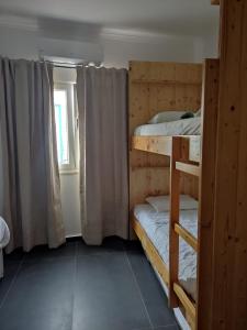 zwei Etagenbetten in einem Zimmer mit Fenster in der Unterkunft Casa de porto covo 2 in Porto Covo