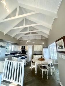 a kitchen with a white table and white chairs at Beach House Princes Grant Golf Estate in Blythedale