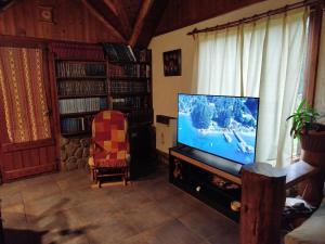 a living room with a flat screen tv and a chair at Casa Los Coihues in Villa La Angostura