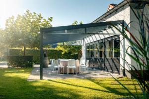 a pergola with a table and chairs in a yard at Villa 't Boshuys - a private and green location for families or friends up to 16 guests in Den Ham