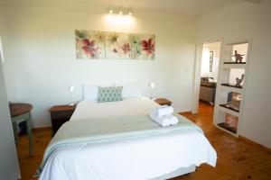 a bedroom with a white bed with a white pillow on it at Bo-den-See Cottage in Groot Brak Rivier