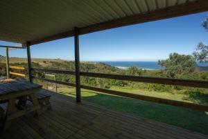 a deck with a table and a view of the ocean at Bo-den-See Cottage in Groot Brak Rivier