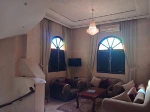a living room with a couch and two windows at Villa Lmima Malika in Marrakesh