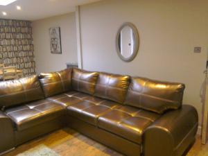 a leather couch in a living room with a mirror at The Dorchester Serviced Apartments in Hull