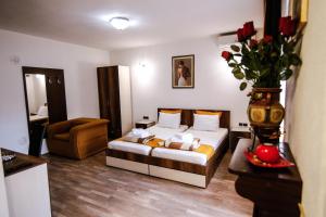 a bedroom with a bed and a vase with roses at Apartmani Centar Kumanovo in Kumanovo