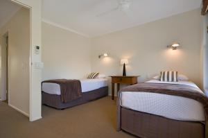 a bedroom with two beds and a table with a lamp at Skippers Cove Waterfront Resort in Noosaville +25 photos