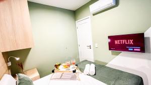 a room with a tv and a bed with a table at Flats no centro de Porto de Galinhas próximo à praia opções com e sem piscina privativa in Porto De Galinhas