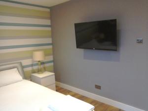 a bedroom with a bed and a flat screen tv on the wall at The Dorchester Serviced Apartments in Hull