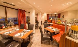 restauracja z drewnianymi stołami i krzesłami oraz oknami w obiekcie Hotel Glasererhaus w mieście Zell am See