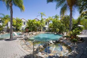 uma piscina com palmeiras em frente a uma casa em Skippers Cove Waterfront Resort em Noosaville