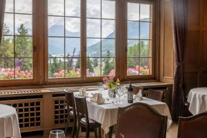 un comedor con mesas y ventanas con montañas en Hotel Chesa Spuondas, en St. Moritz