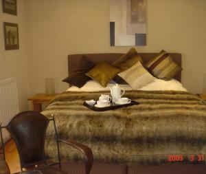 Una cama con una bandeja con dos tazas. en Annesdale House en Windermere