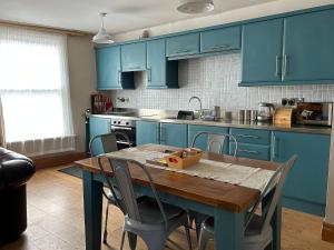 a kitchen with blue cabinets and a wooden table at The Pebbles in Whitby