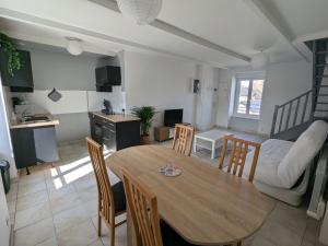 a kitchen and living room with a wooden table and chairs at Duplex sur la Baie in Saint-Benoît-des-Ondes