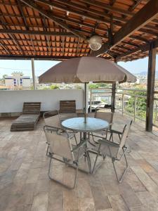 ein Tisch mit Stühlen und einem Sonnenschirm auf einer Terrasse in der Unterkunft Suite casal 2 com frigobar in Belo Horizonte