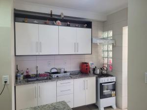 サンタ・ローザにある1 dorm privativo casalの白いキャビネットとコンロ付きオーブンを備えたキッチン