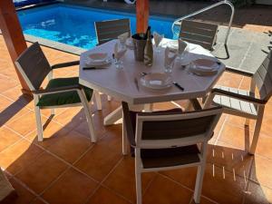 a white table and chairs with a table and a pool at Villa Maiteren Etxea- 4 Beds property with private pool in Playa Blanca