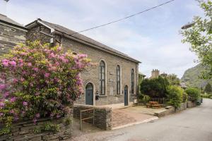 an old brick church with pink flowers in front of it at Capel Salem by Birch Stays in Blaenau-Ffestiniog