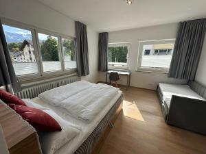a bedroom with a bed and a desk and windows at DAS LUDWIG - Haus HOCHLAND in Garmisch-Partenkirchen