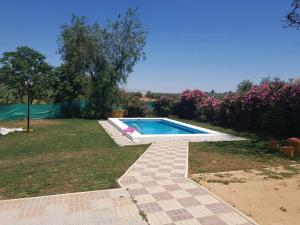 a swimming pool in a yard with pink flowers at Lo Conseguí in Bollullos de la Mitación