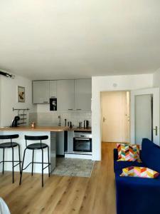 a kitchen and a living room with a blue couch at Charmant studio in Roissy-en-France
