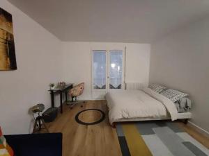a white bedroom with a bed and a window at Charmant studio in Roissy-en-France