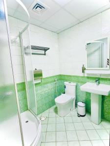a green tiled bathroom with a toilet and a sink at Galaxy Star Hotel in Dubai +67 photos