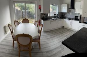 a kitchen with a table and chairs and a kitchen with white cabinets at 5 Bed house in Sittingbourne Kent in Kent