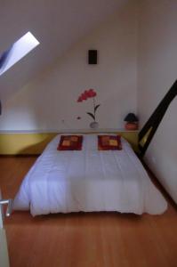 サン・ジュニアンにあるGite Des Noisetiersのベッドルーム1室(赤い花の白いベッド1台付)