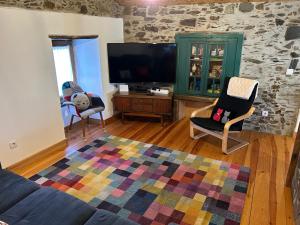 uma sala de estar com uma televisão e um sofá e cadeiras em Casa do Gato em Góis