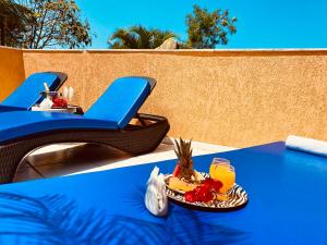 a blue table with a plate of fruit and a glass of orange juice at Villa Baobá Pousada & Spa in Búzios