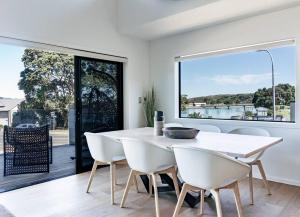 a dining room with a table and chairs and a large window at Wainui Townhouses in Raglan