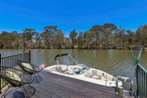 een kleine boot geparkeerd op een steiger op een meer bij DOCK 08 Riverside Entertainer Pets Welcome in Chittaway Point