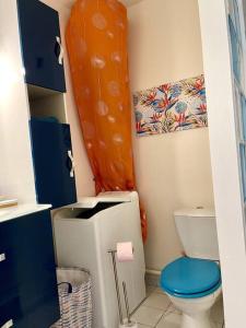 a bathroom with a toilet and an orange curtain at Appartement face mer in Le Moule +34 photos