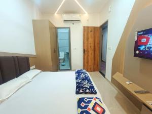 a bedroom with a bed and a tv and a bathroom at Shri Radha Rani Kripa Dham in Mathura