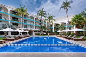 a pool in front of a hotel with chairs and palm trees at Hotel Suites Villasol in Puerto Escondido