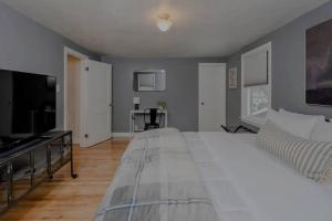 a bedroom with a large white bed and a flat screen tv at Wilson Street Home in Little Chute