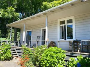 a porch of a house with a table and chairs at The Rabbiter's Cottage in Kahuranaki