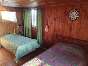 a bedroom with two beds in a wooden cabin at Alojamiento en ambiente campestre, para disfrutar libre del ruido de la ciudad y del ajetreo del trabajo in Parral