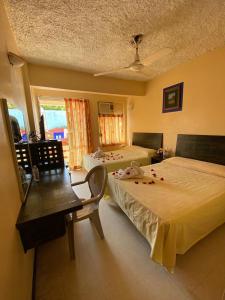 a bedroom with two beds and a table and a desk at Hotel Zihuatanejo Centro in Zihuatanejo +21 photos