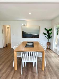 a dining room with a wooden table and white chairs at Whale Bay's Surf Meca holiday accommodation in Raglan