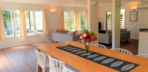 a living room with a table with a vase of flowers on it at Whale Bay's Surf Meca holiday accommodation in Raglan