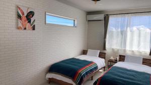 a bedroom with two beds and a window at Pleasure Point Ichinomiya in Ichinomiya