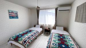 a bedroom with two beds and a window at Pleasure Point Ichinomiya in Ichinomiya