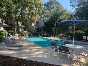 a pool with chairs and a table and an umbrella at Lovely 3 Bed3 Bath Pet FriendlyVilla - Walk to the beach pools and tennis #75 Ocean Breeze in Hilton Head Island