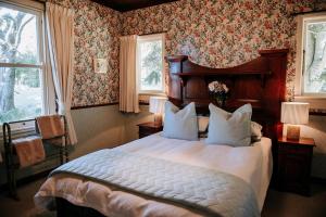 a bedroom with a large bed with floral wallpaper at The Rabbiter's Cottage in Kahuranaki