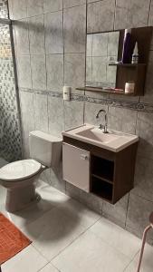 un bagno con un water, un lavandino e uno specchio di Linda casa Morada da Praia com piscina privativa e muito espaço pra você e seu pet a Bertioga