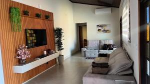 un soggiorno con un divano e una televisione di Linda casa Morada da Praia com piscina privativa e muito espaço pra você e seu pet a Bertioga